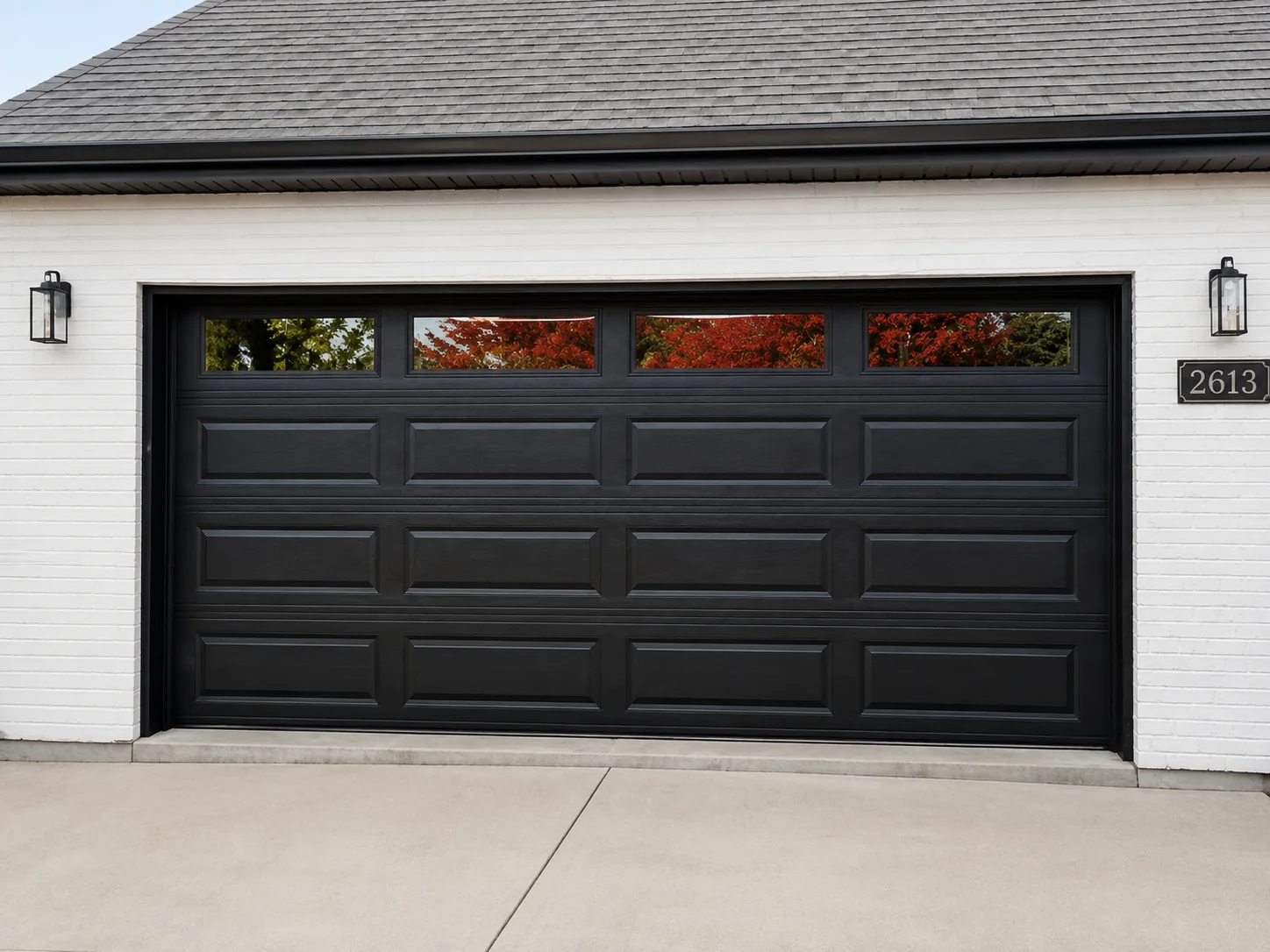 Black double garage door on a white brick home