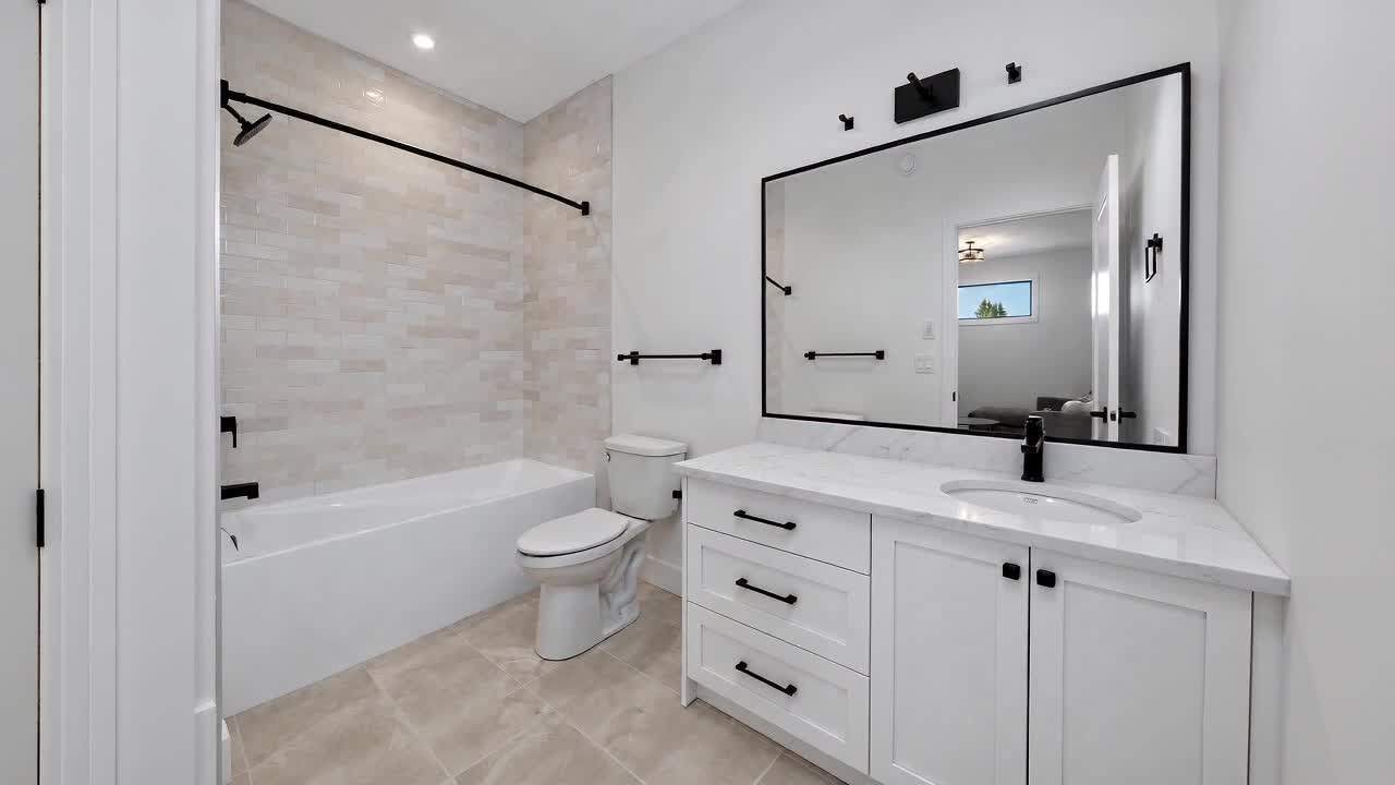 Renovated bathroom with a black-framed mirror being installed over the vanity