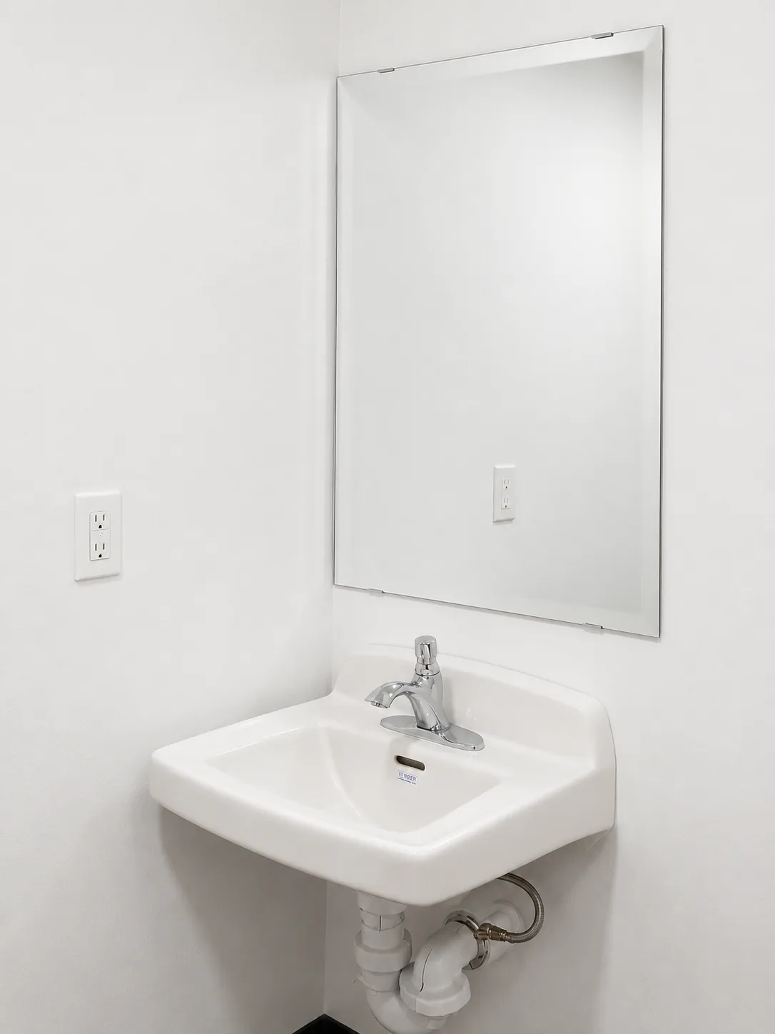Frameless mirror over a wall-hung basin