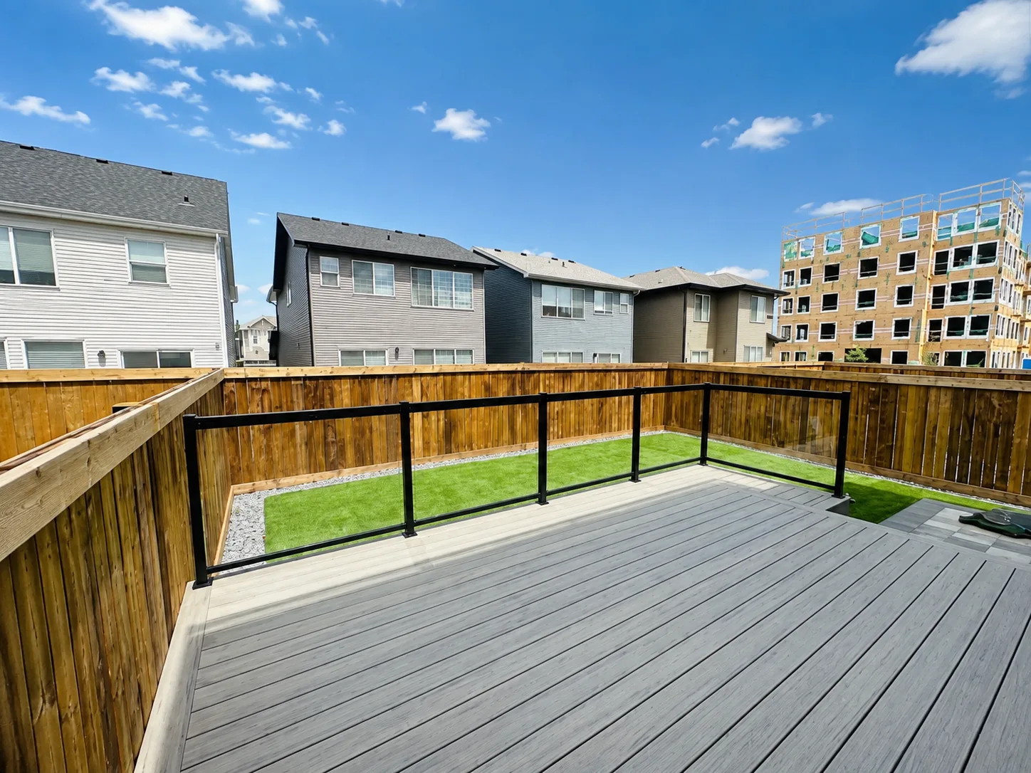 Black-framed glass deck railing around a composite deck