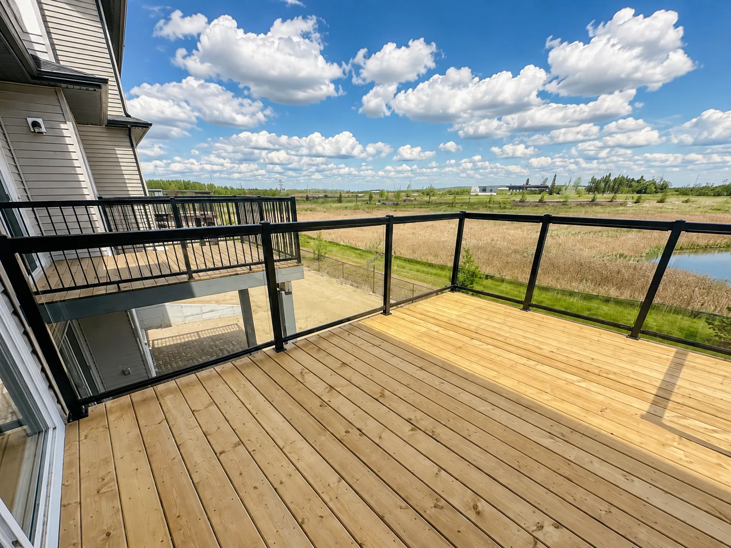 Glass railing on a wood deck overlooking a wetland