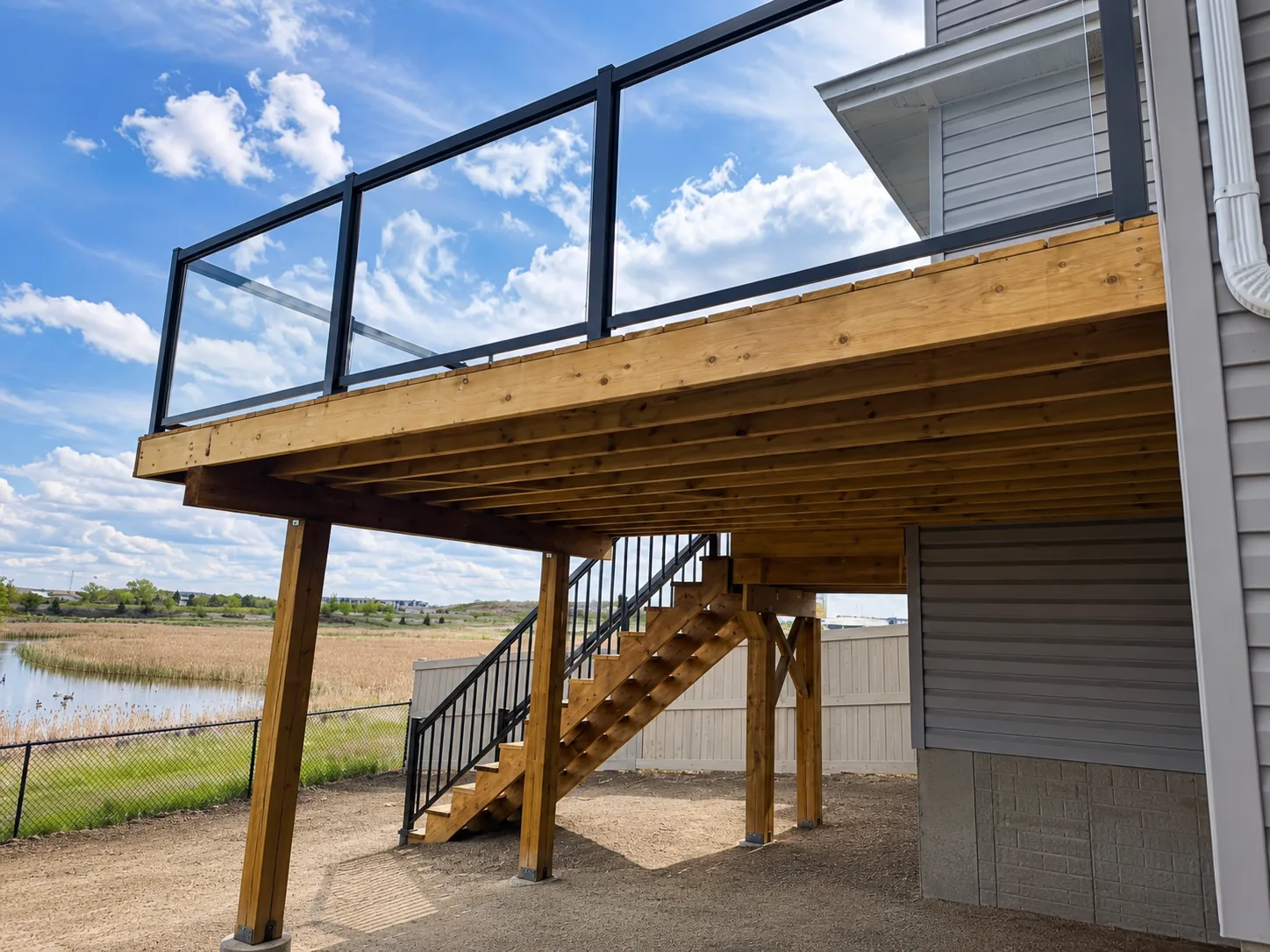 Elevated deck with glass railing panels and wood stairs