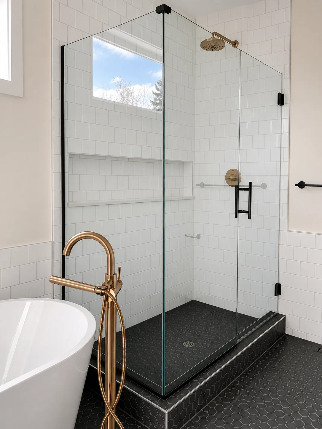 Frameless hinged enclosure with brass hardware beside a freestanding tub