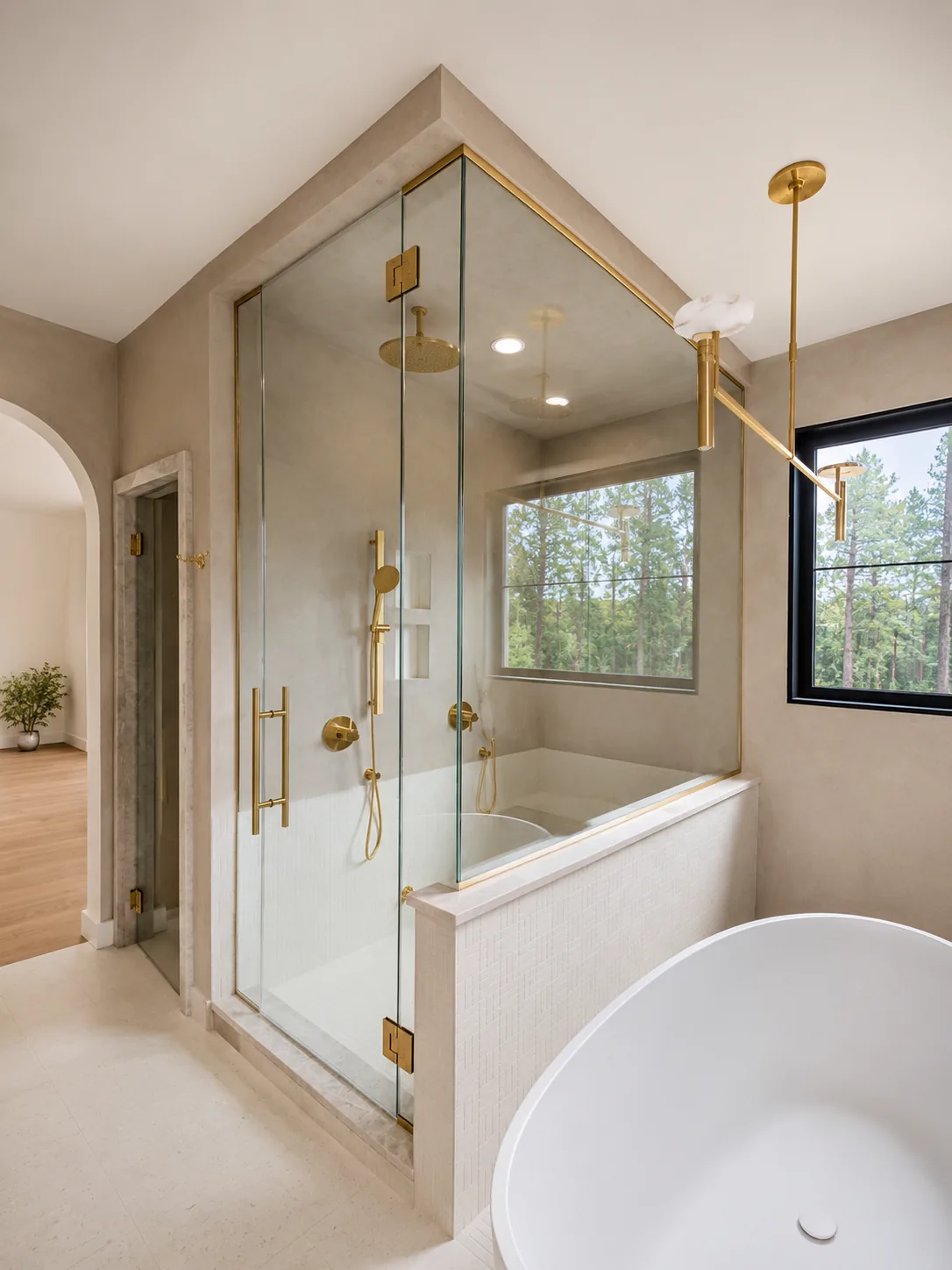 Brass-trimmed frameless shower with a freestanding tub and arched doorway